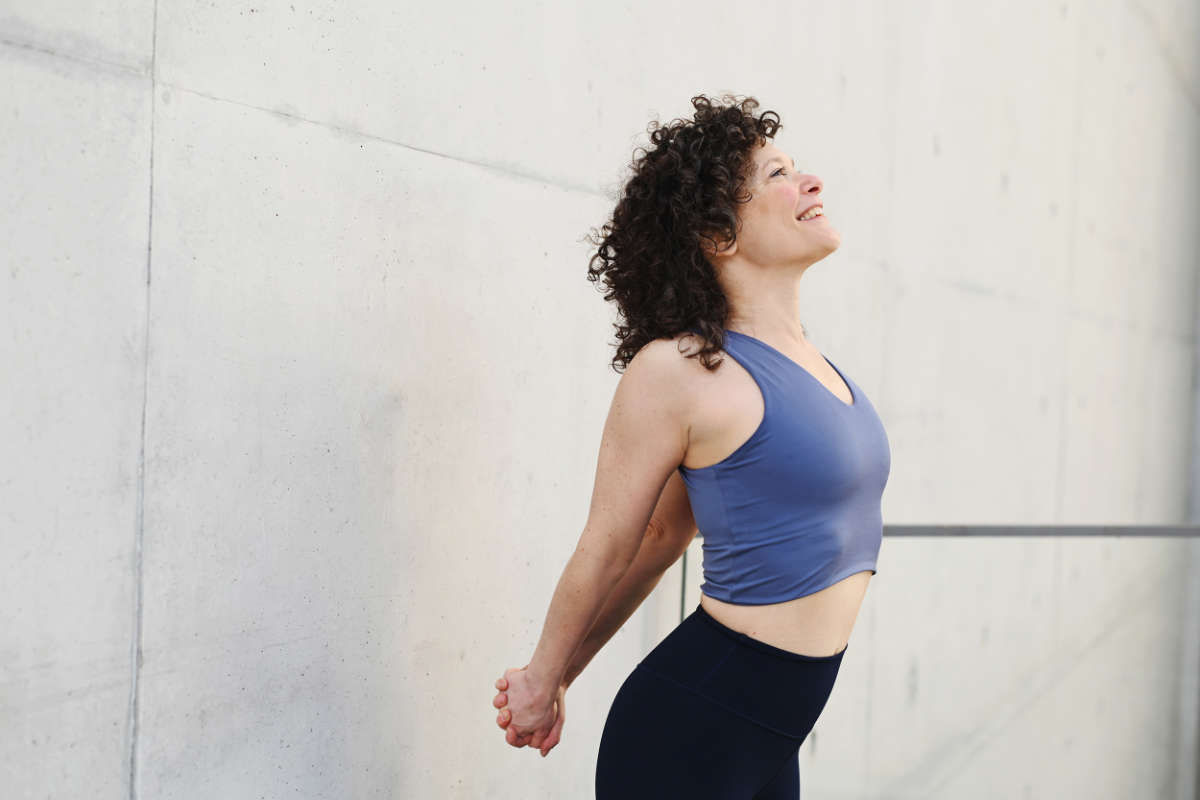 Barbara Pascaly in einer Yoga-Dehnung mit nach hinten verschränkten Händen bereit für das Yoga Retreat im Vju Hotel auf Rügen.
