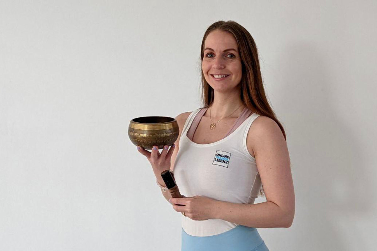 Kati Bloehdorn lächelt mit Klangschale in der Hand - bereit für eine Klangmeditation beim Yoga Retreat im Vju Hotel.