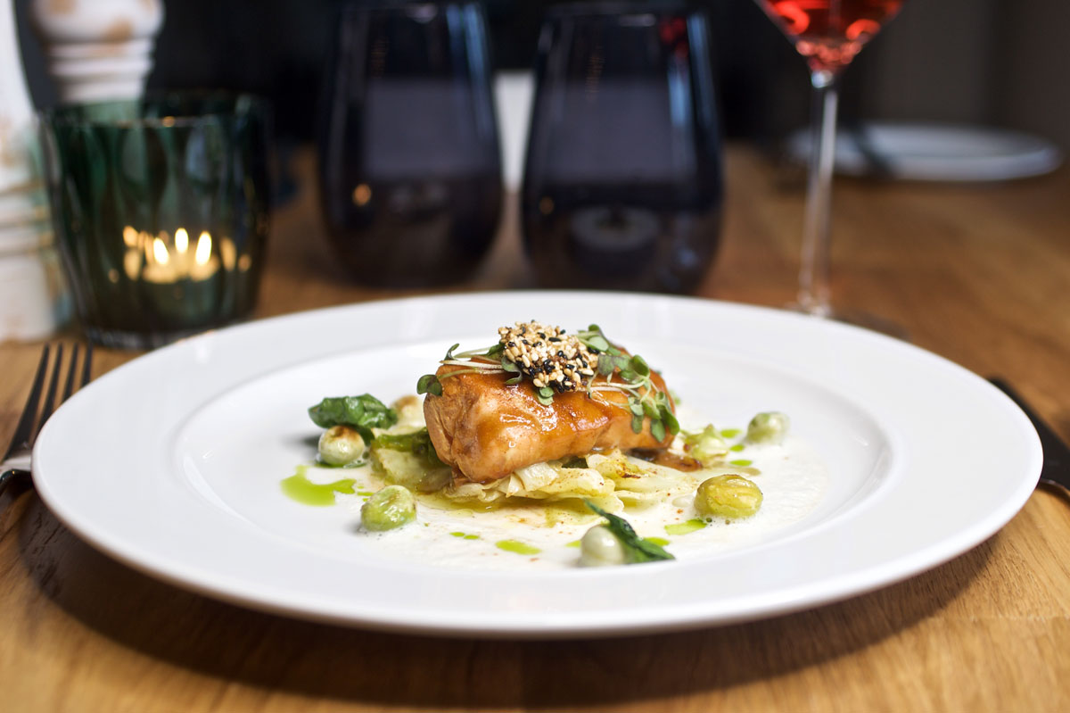 Edles Fischgericht mit knuspriger Kruste, Gemüsebeilage und feiner Soße im Restaurant des Vju Hotels.