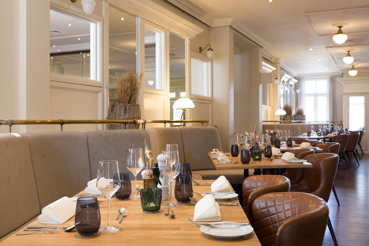 Edles Restaurant Strandläufer mit gedeckten Tischen, stilvoller Beleuchtung und gemütlichem Ambiente im Vju Hotel.