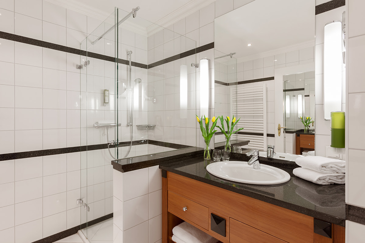 Bright hotel bathroom with glass shower, make-up mirror and fresh towels in the double room of the Vju Hotel annexes.