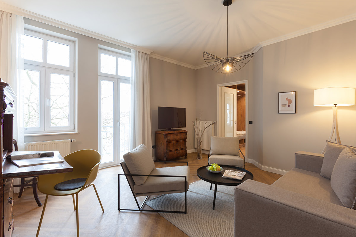 Modern eingerichtete Familiensuite mit Sitzecke, Holzmöbeln und dezenten Farben im Vju Hotel auf Rügen.