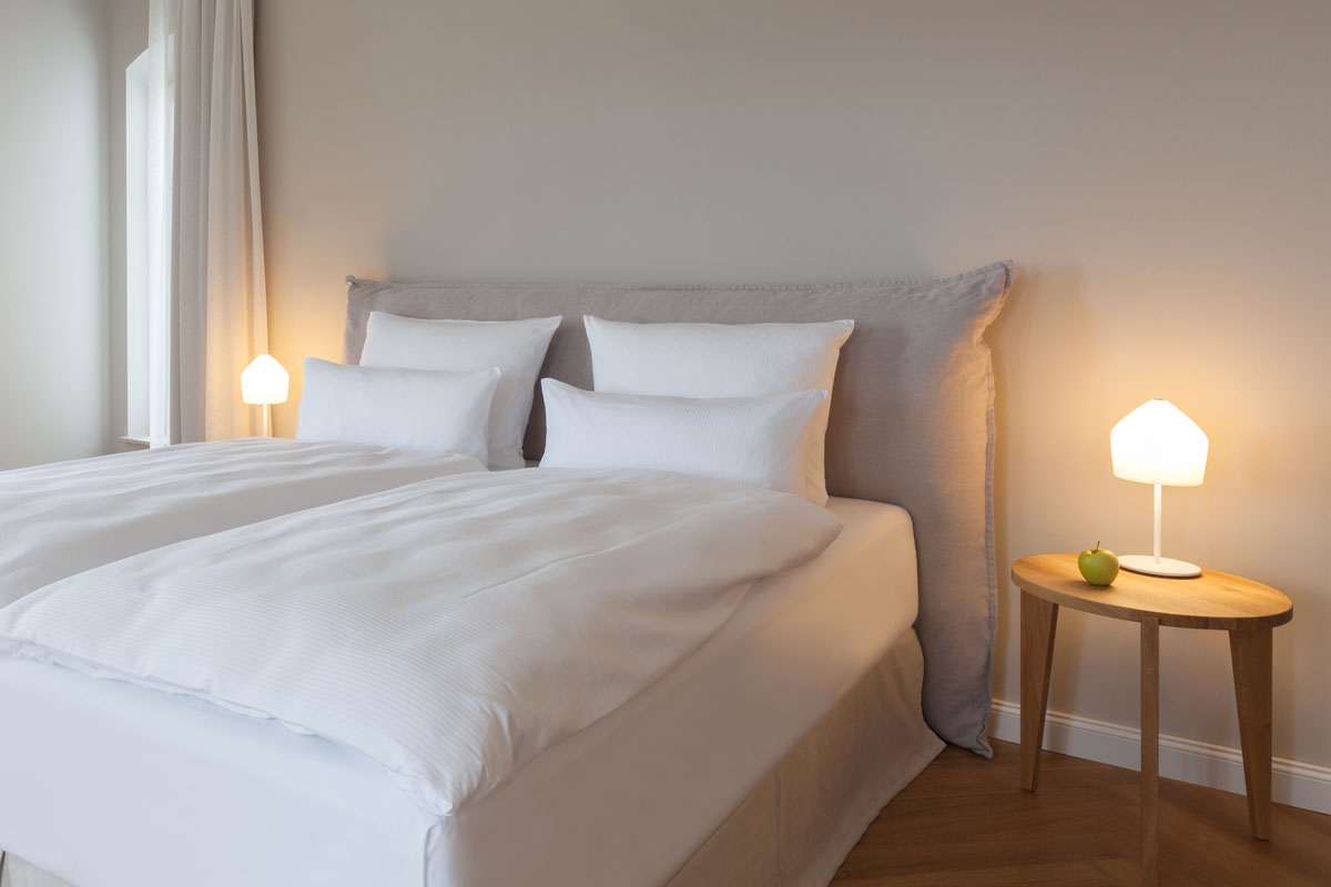 Stilvolles Schlafzimmer mit hochwertigem Bett und gemütlicher Atmosphäre im Doppelzimmer des Vju Hotels.