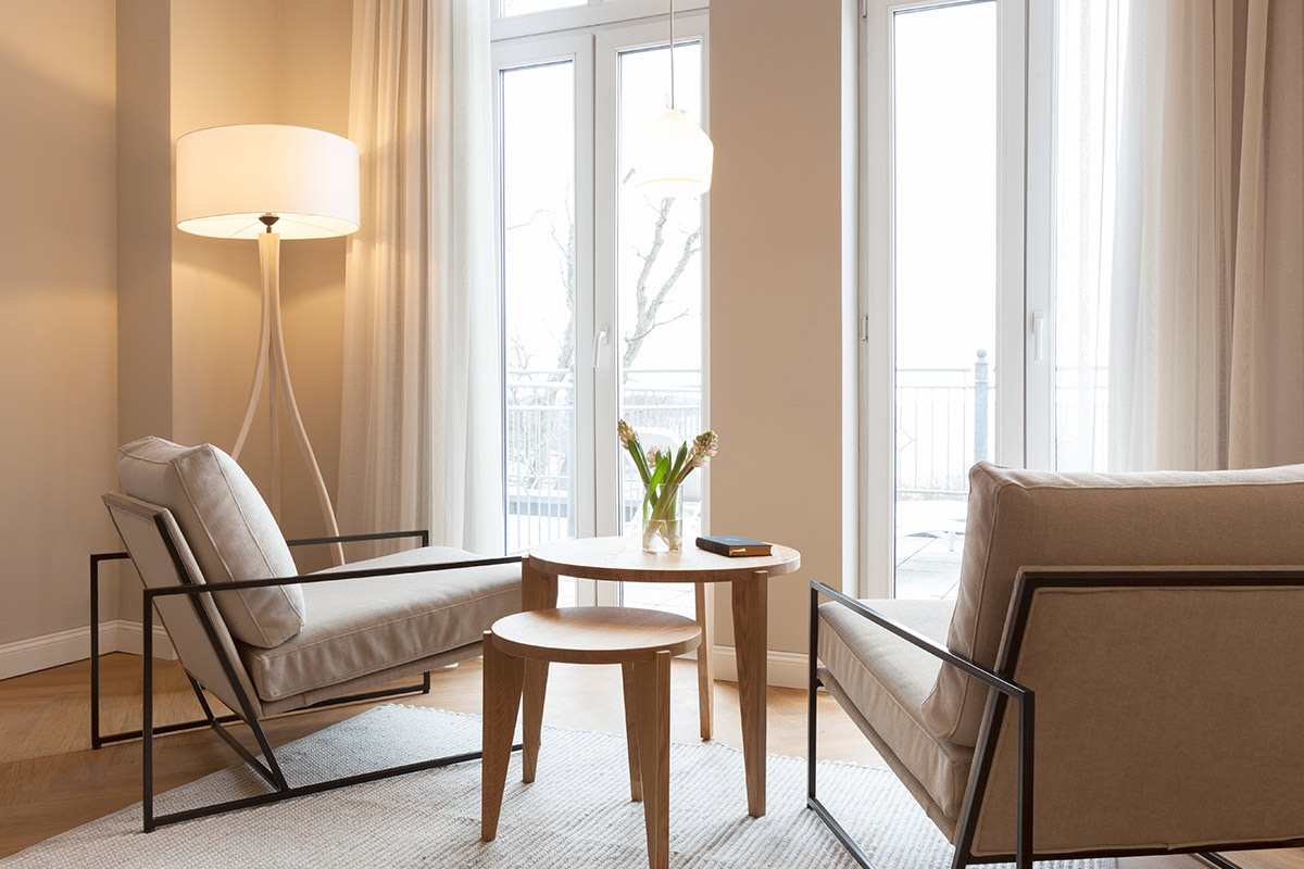 Bright seating area with two armchairs and floor-to-ceiling windows in the studio with a view of the Baltic Sea at the Vju Hotel.