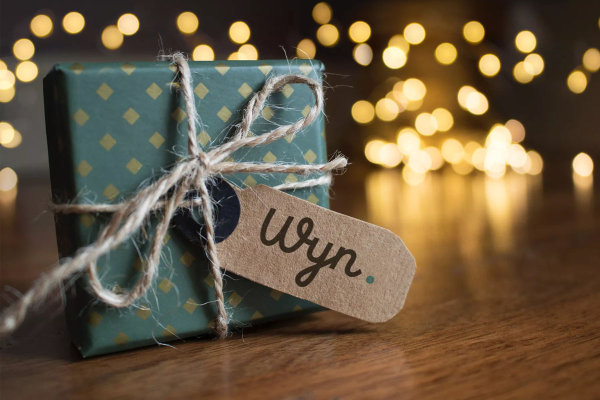 Ein liebevoll verpacktes Geschenk mit Wyn-Etikett vor festlicher Beleuchtung zu Weihnachten im Wyn. Strandhotel auf Sylt.