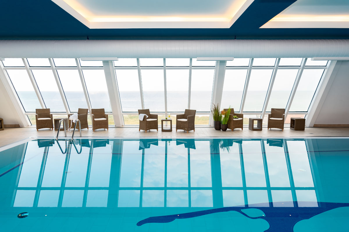 Indoorpool mit großen Glasfenstern und Blick auf die Nordsee, perfekt für Urlaubsangebote vom Wyn. Strandhotel auf Sylt.