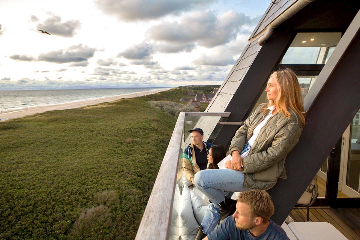 Gruppe entspannt auf dem Balkon des Wyn Strandhotel Sylt mit Blick auf Strand und Dünen