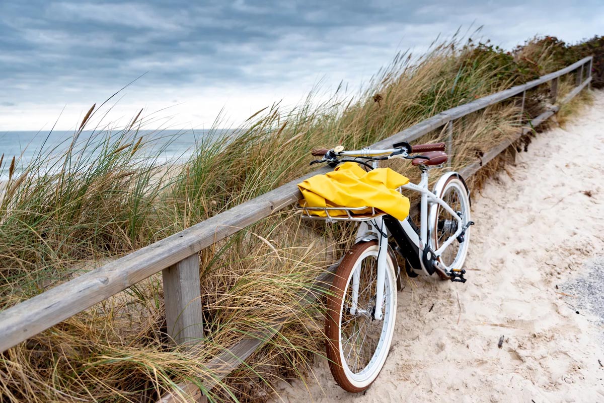 Fahrrad mit gelber Tasche am Strandweg, im Hintergrund Dünen und das Meer als Teil der Urlaubsangebote vom Wyn. Strandhotel.