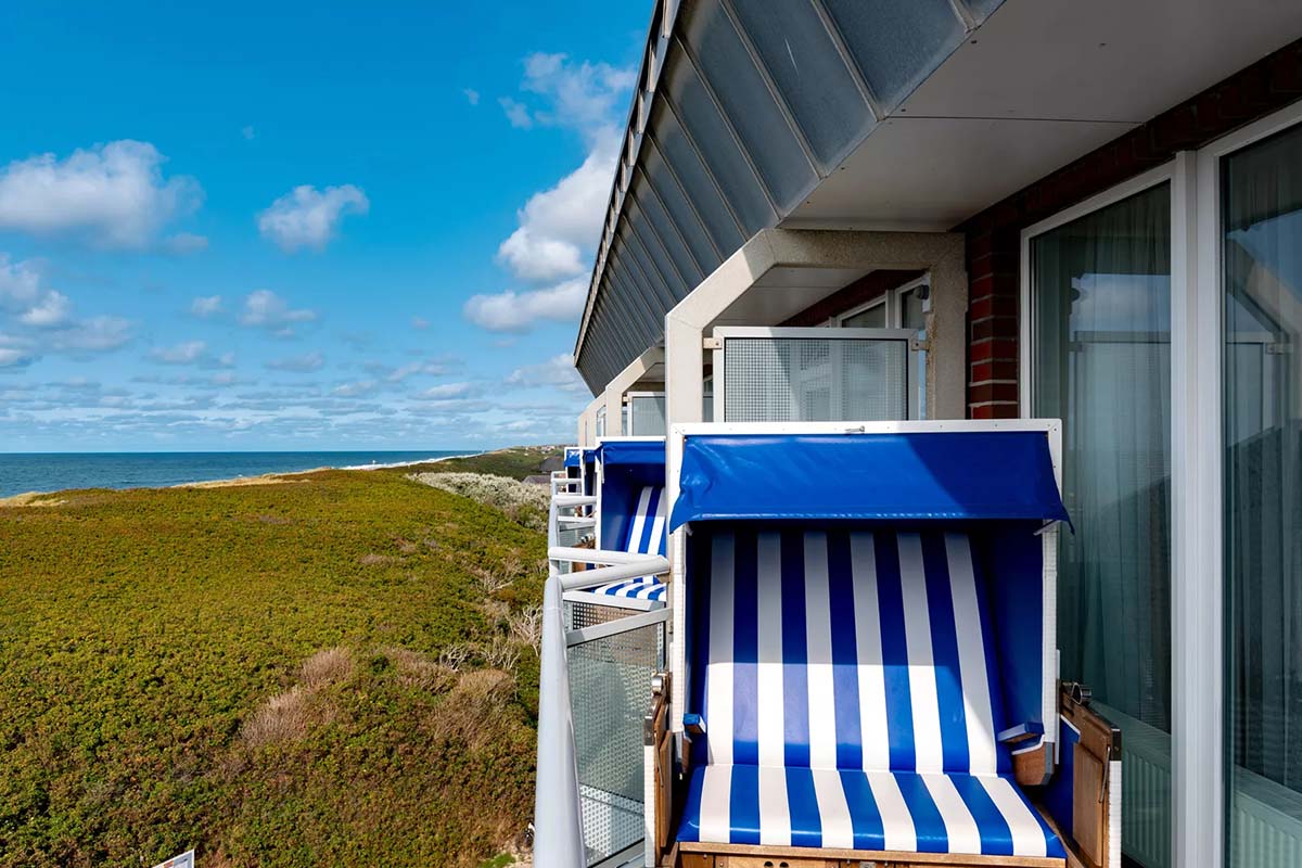 Privater Balkon im Meerzeit-Zimmer des Wyn. Strandhotels mit Strandkorb und atemberaubender Aussicht auf die Küste von Sylt.