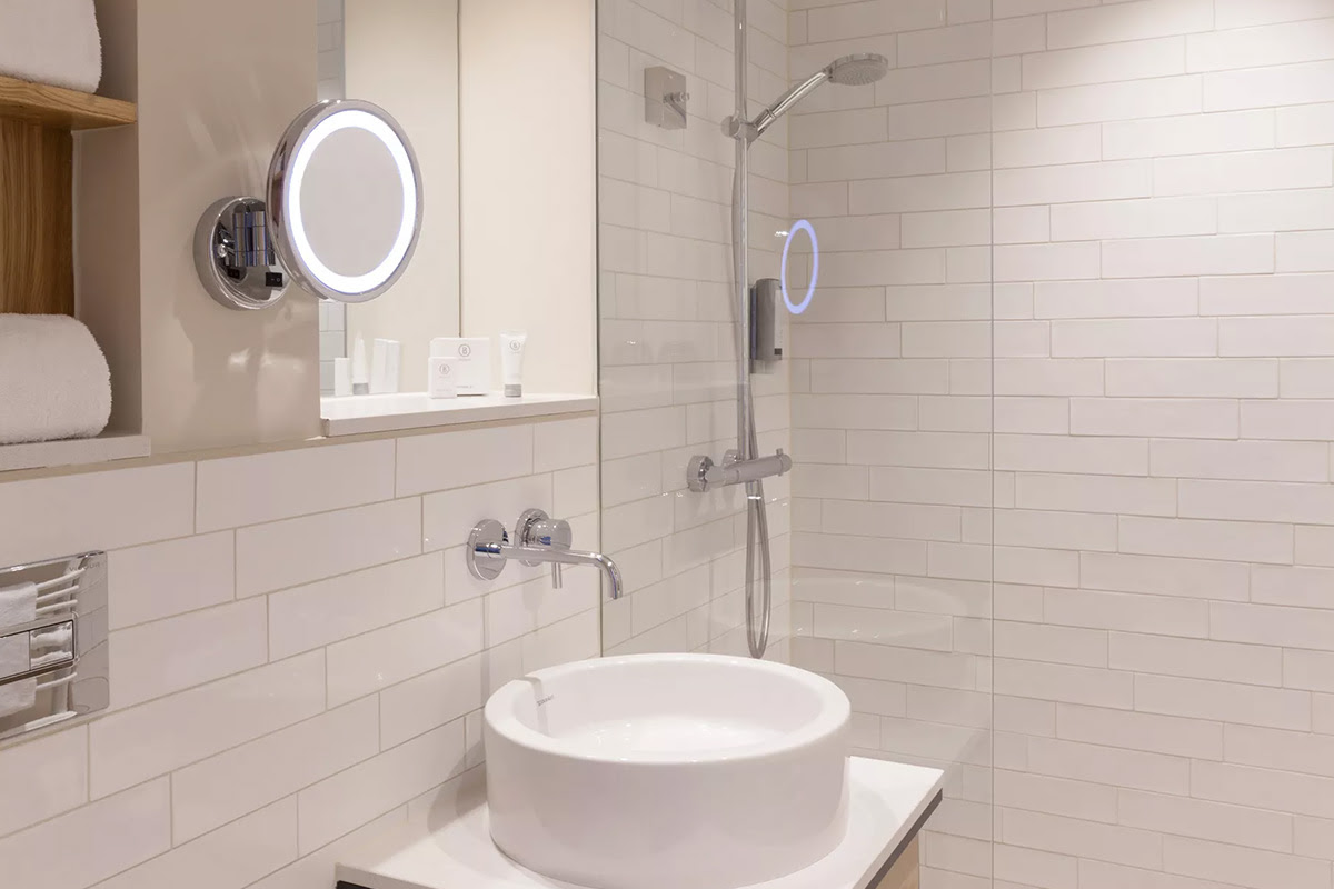 Helles Hotelbad des Meerzeit Zimmers im Wyn. Strandhotel mit großzügiger Glasdusche, modernem Waschbecken und stilvollen Fliesen.