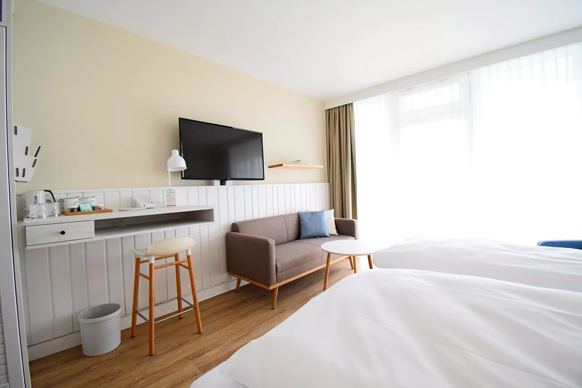 Moderne Lounge-Ecke im Zimmer Meerzeit mit Design-Sofa und Ausblick – perfekt für einen Urlaub im Wyn. Strandhotel auf Sylt.