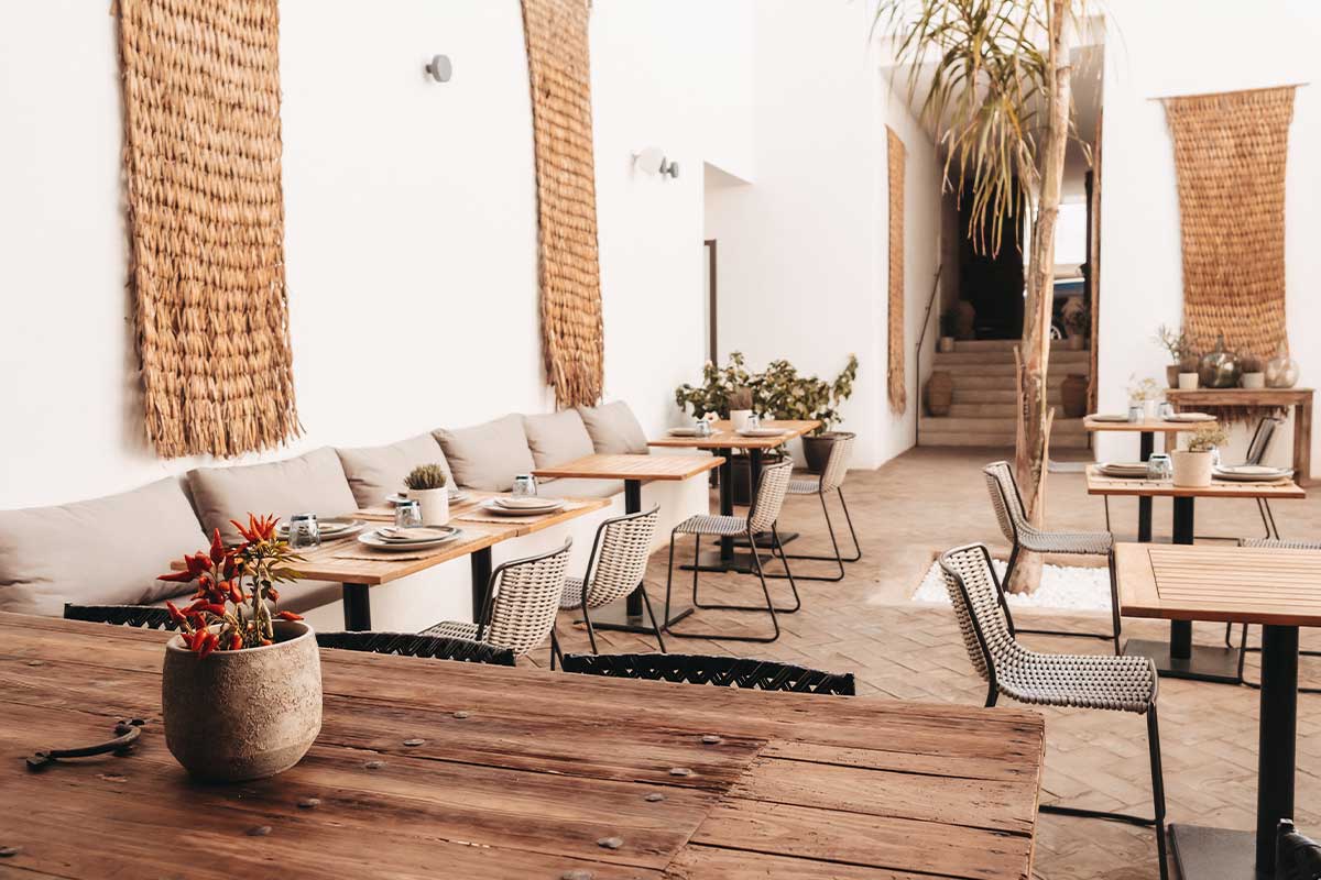 Blick in das moderne Barefoot Restaurant mit hellen Sesseln, Holzdekor und eingedeckten Tischen im Barefoot Hotel auf Mallorca.