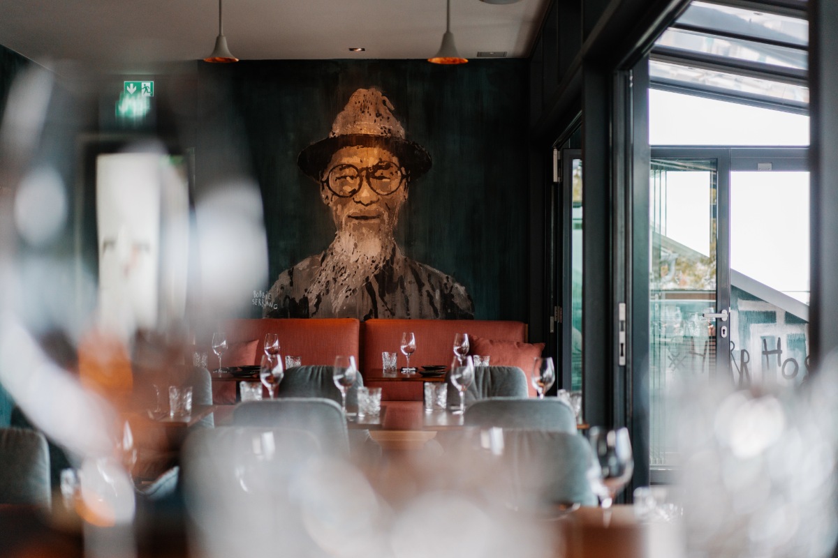 Stilvoll eingedeckter Innenraum des Restaurants #herrhoshi mit Porträtmalerei im Hotel Künstlerquartier Seezeichen in Ahrenshoop.