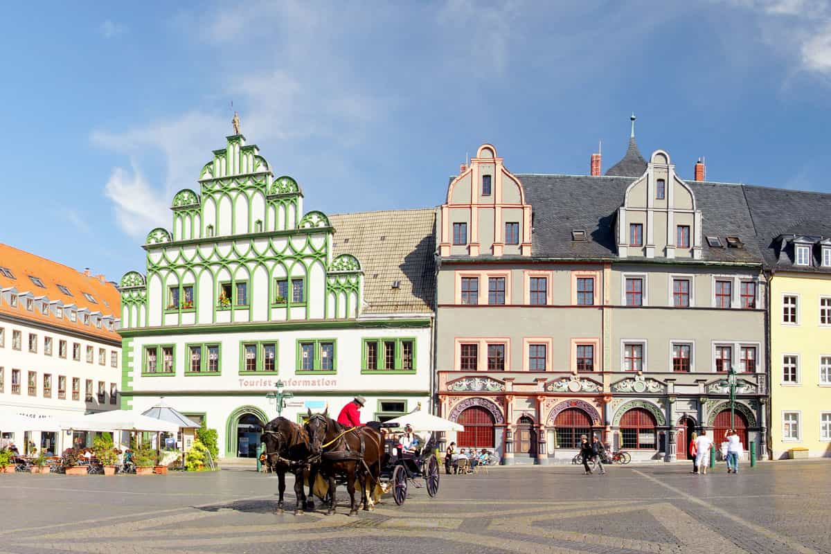 Blick auf die historische Innenstadt von Weimar mit Pferdekutsche und Menschen im Hintergrund.