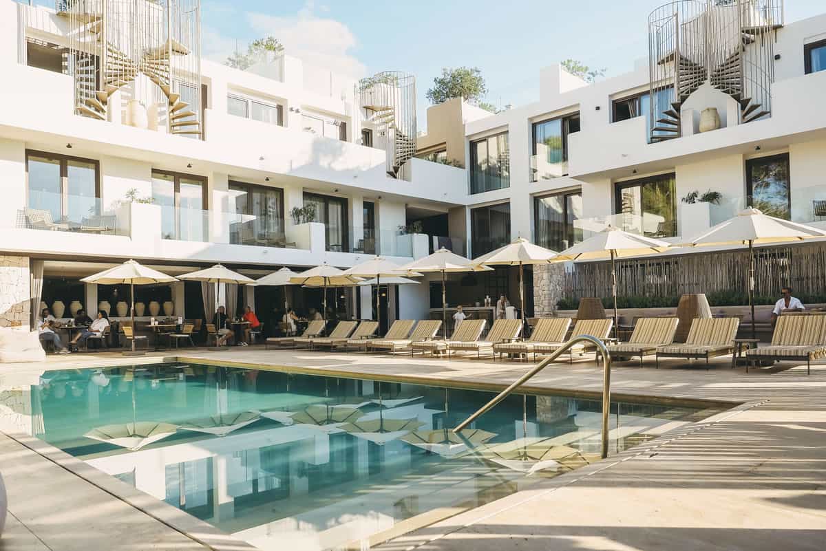 Blicken Sie auf das Barefoot Hotel in Mallorca, umgeben von sonnigen Liegen, Sonnenschirmen und einem erfrischenden Pool.