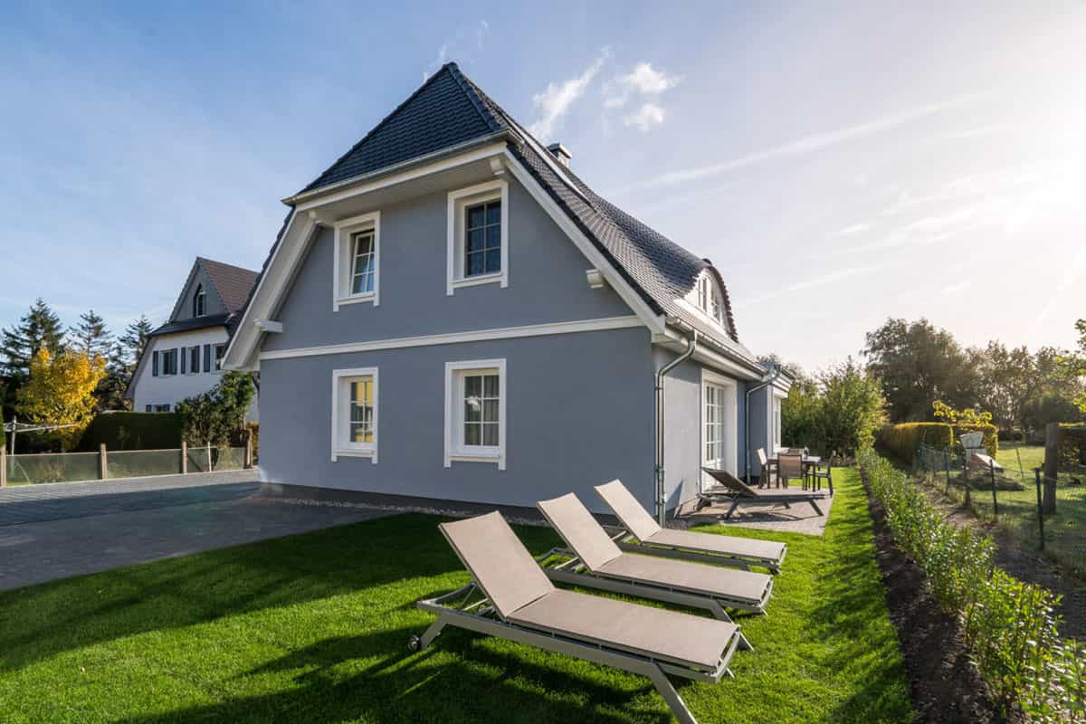 Ferienhaus Sonneninsel mit blauer Fassade, Garten, Sonnenliegen und sonnigem Himmel in Ahrenshoop.