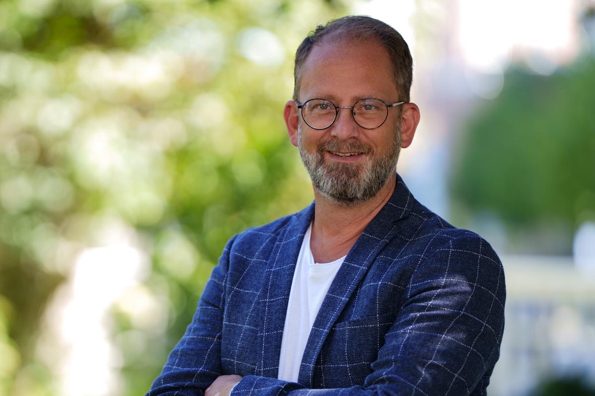 Geschäftsführer der arcona Hotels und Resorts Alexander Winter steht lächelnd vor der Kamerea.