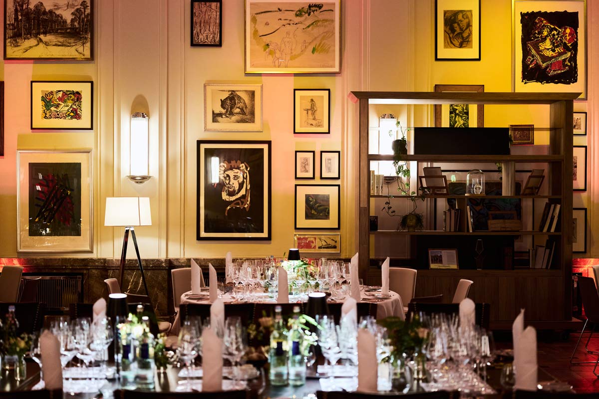 Eleganter Saal mit kunstvoll dekorierten Wänden, gedeckten Tischen und einer warmen, gemütlichen Atmosphäre.