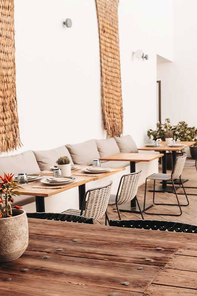 Blick in das moderne Barefoot Restaurant mit hellen Sesseln, Holzdekor und eingedeckten Tischen im Barefoot Hotel auf Mallorca.