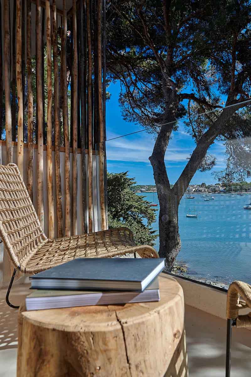 Terrasse mit Ausblick auf das Meer, Holzmöbel und mediterrane Landschaft im Barefoot Hotel Mallorca.