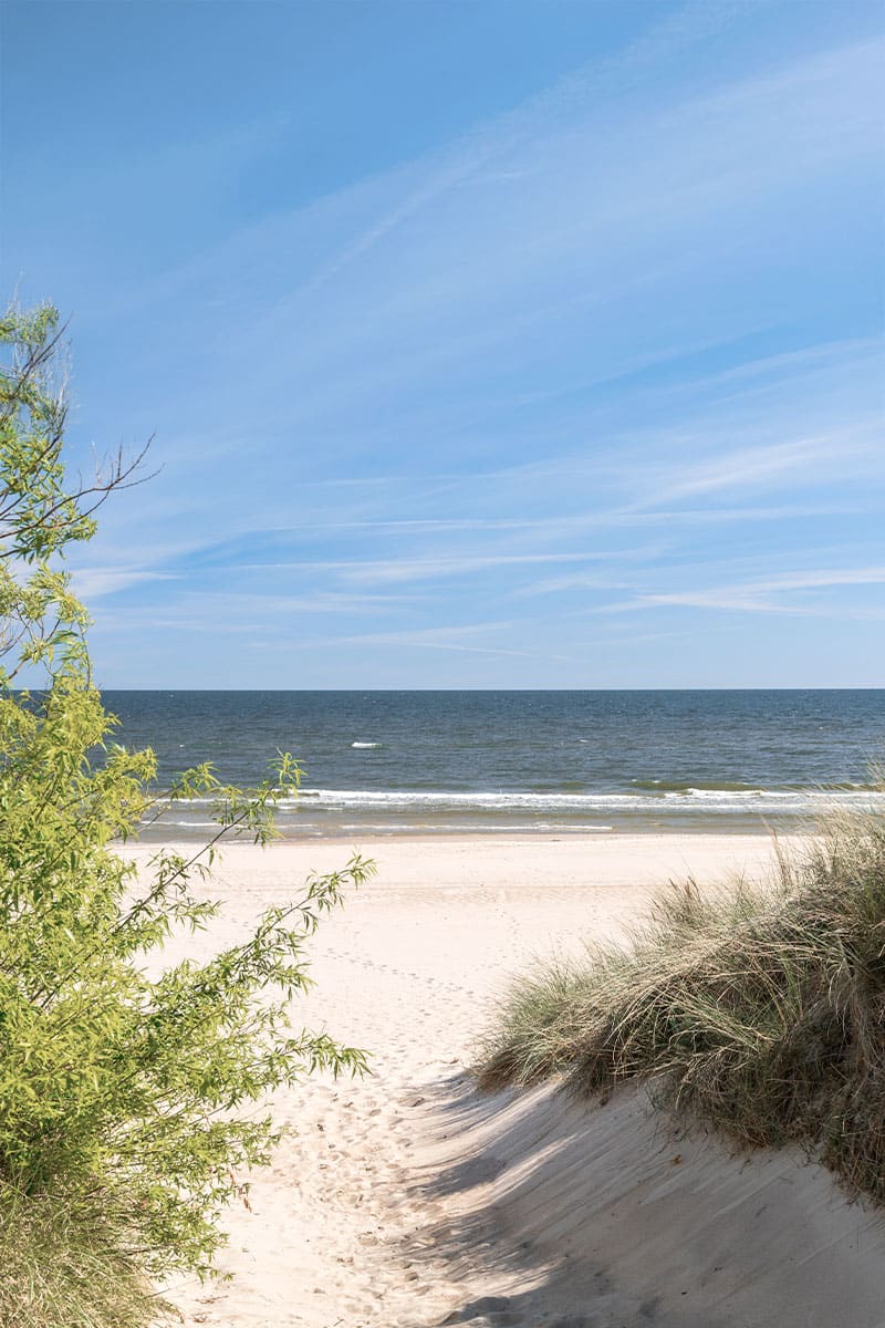 Strandaufgang durch Dünen auf Usedom, ruhiges Meer im Hintergrund.