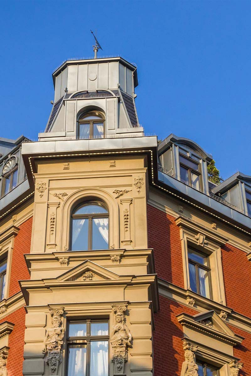 Detailed shot of a historic facade with decorated elements and towers under a blue sky.