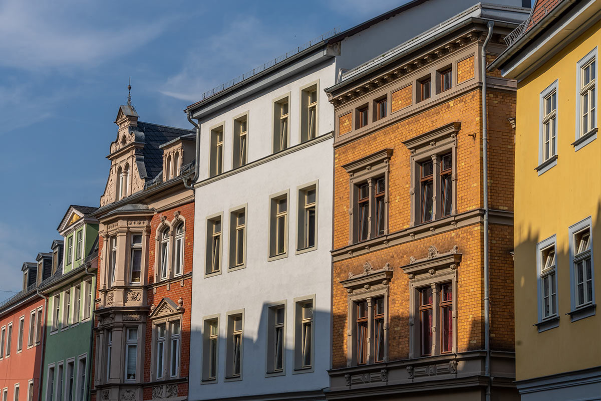 Eine Reihe bunter, historischer Gebäude in der Altstadt Weimars bei strahlendem Sonnenlicht.