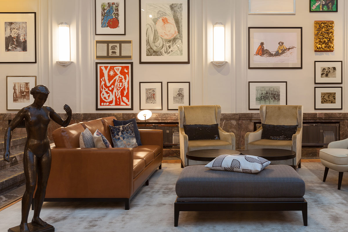 Living area with leather sofa, armchairs and modern art on the walls, decorated with sculptures and cushions.
