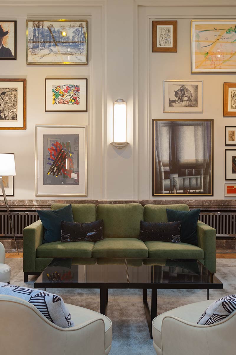 Cozy living area with a green sofa, black cushions and a gallery of artwork on the walls.