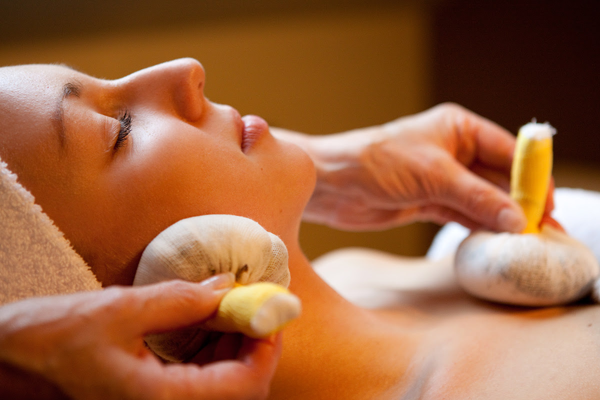 Woman enjoying a facial with two herbal compresses gently applied to her face.