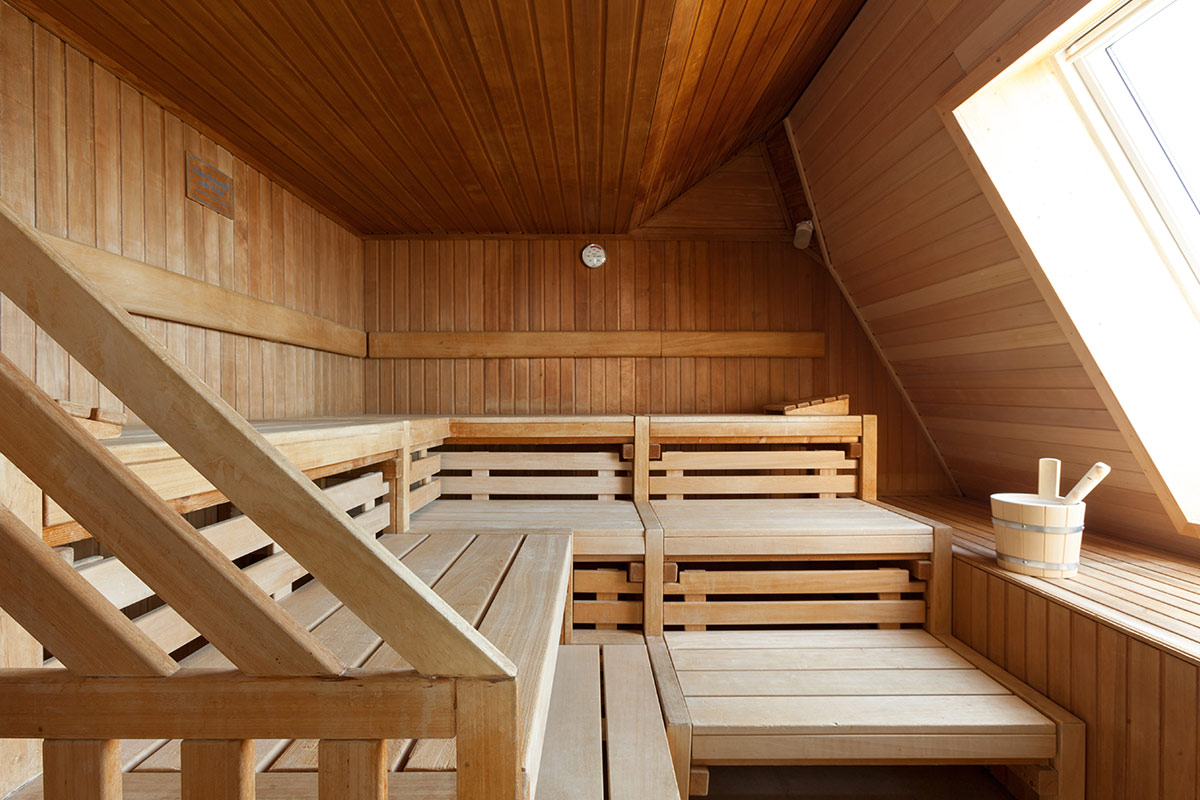 Interior view of a spacious wooden sauna with several rows of seats and natural light.