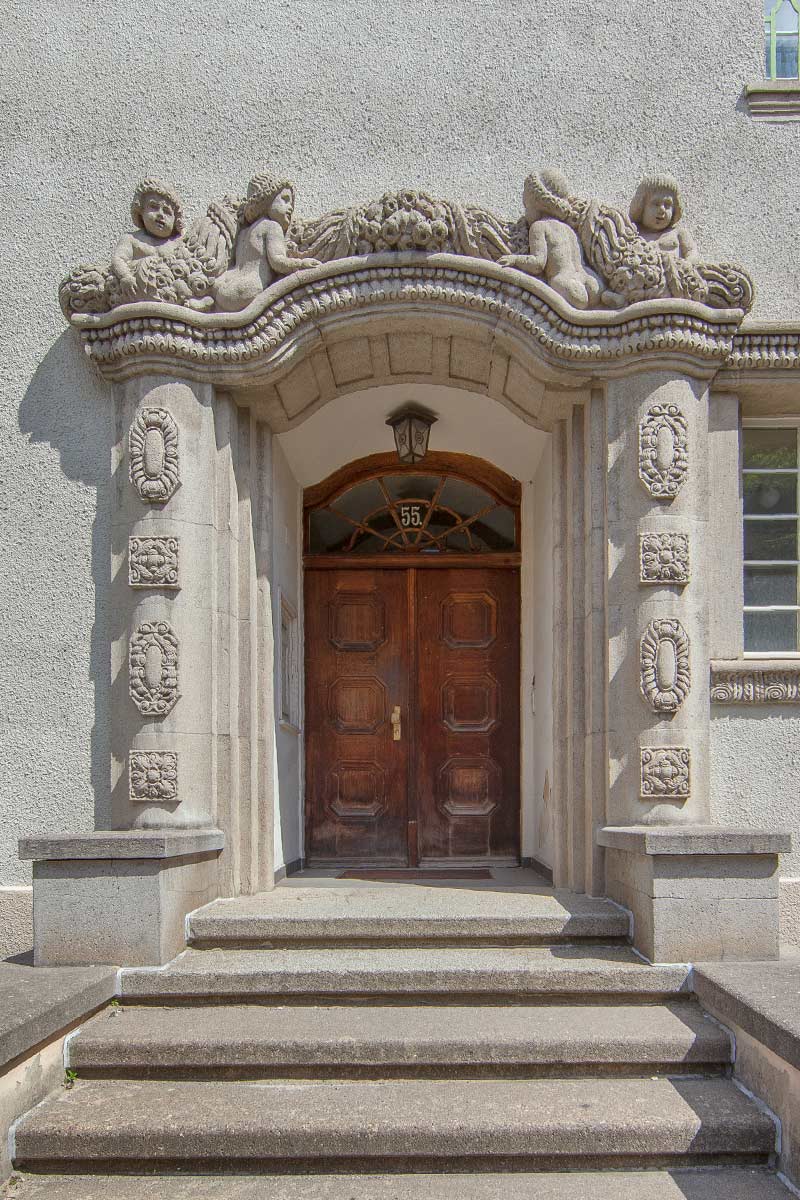 Verzierte Eingangstür mit aufwendigen Skulpturen und steinernen Verzierungen an der Fassade.