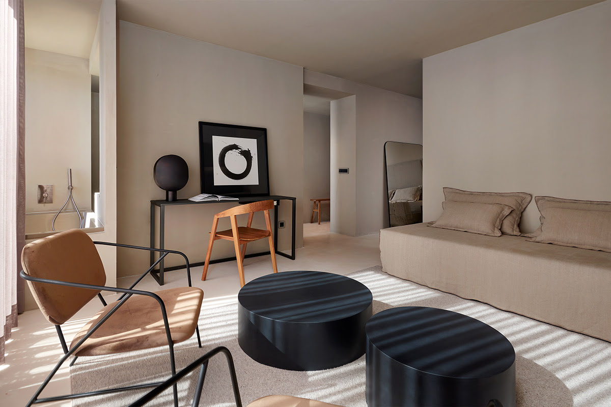 Modernly furnished hotel room with beige furniture, two black tables and large artwork in Mallorca.