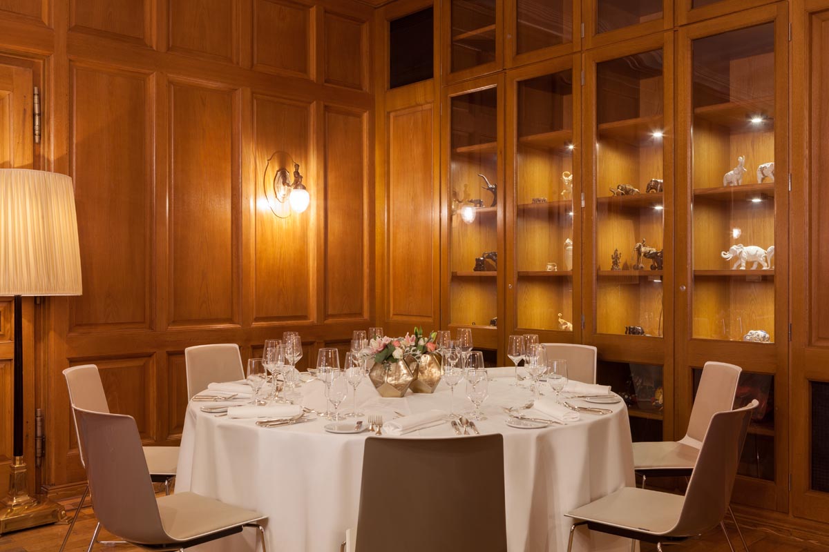 Festively set table in the private dining room of the Hotel Elephant Weimar with wooden paneling and decorative display cases.