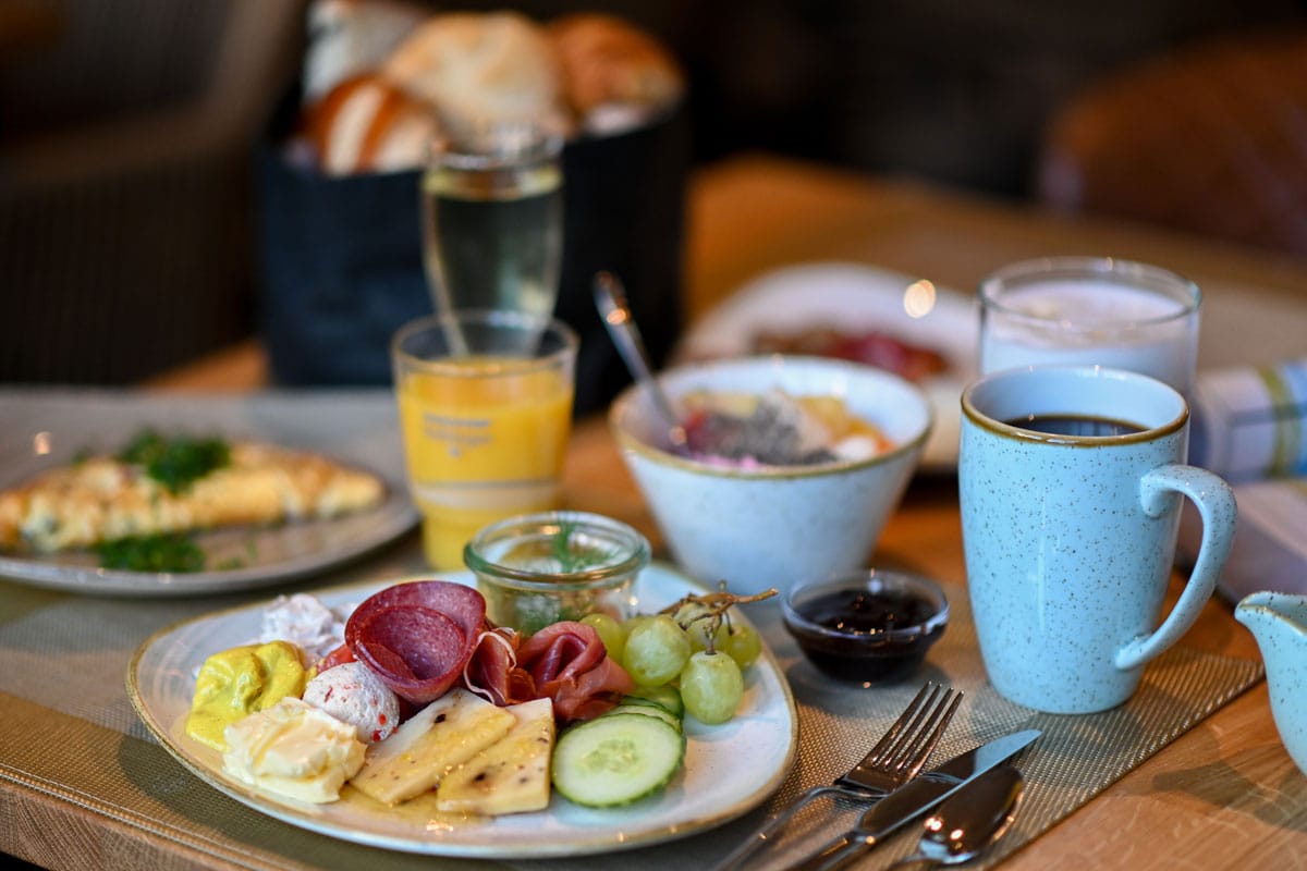 Reichhaltiges Frühstück für Ihren Urlaub im Vju Hotel Rügen mit Kaffee, Orangensaft, Aufschnitt, Käse und frischem Brot.