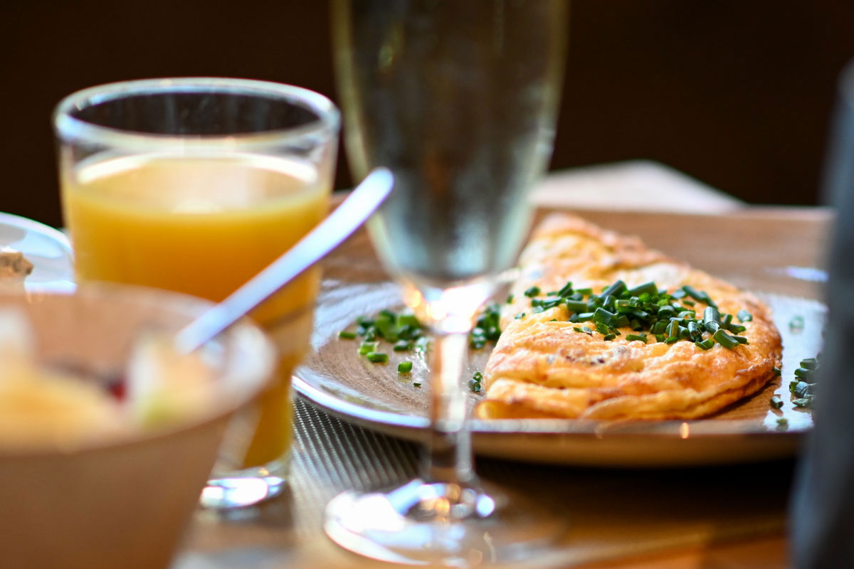 Frühstücksteller im Vju Hotel Rügen mit Omelett mit Schnittlauch und frischem Orangensaft für Kulinarik im Ostseeurlaub.