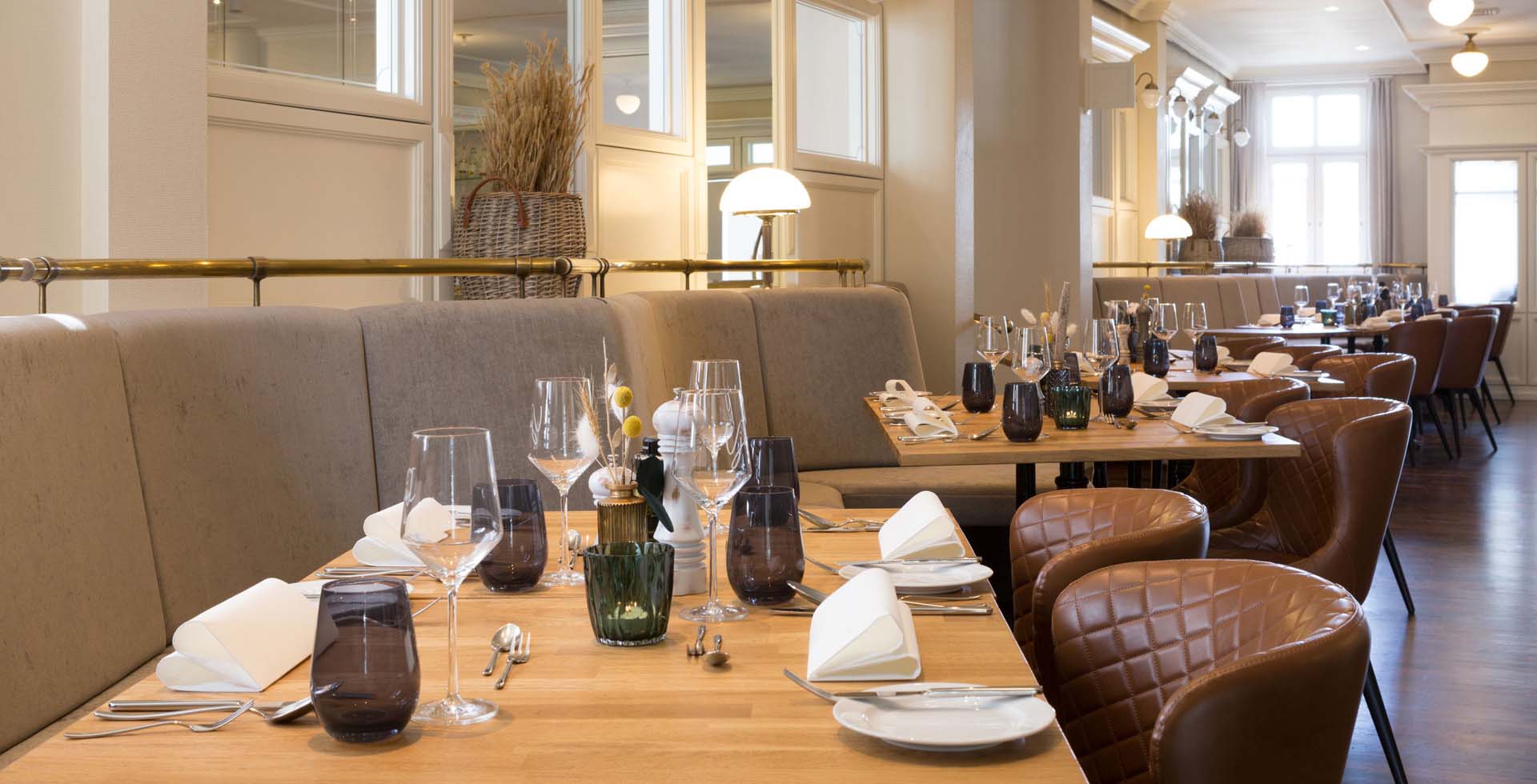 Innenansicht des Restaurants im Vju Hotel auf Rügen mit gedeckten Tischen, modernen Ledersesseln und elegantem Ambiente.