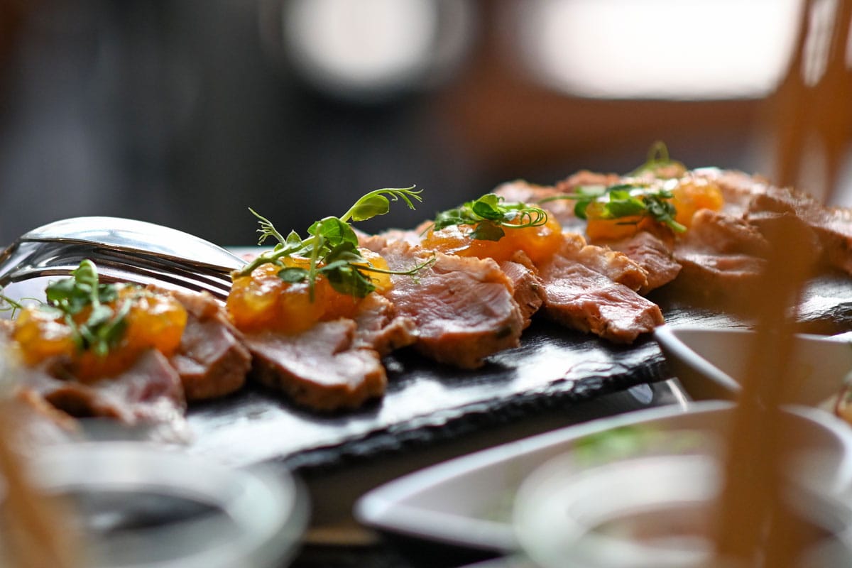 Hochwertig angerichtete Speisen mit Fleisch und Kräutern auf einer dunklen Schieferplatte im Restaurant Strandläufer auf Rügen.