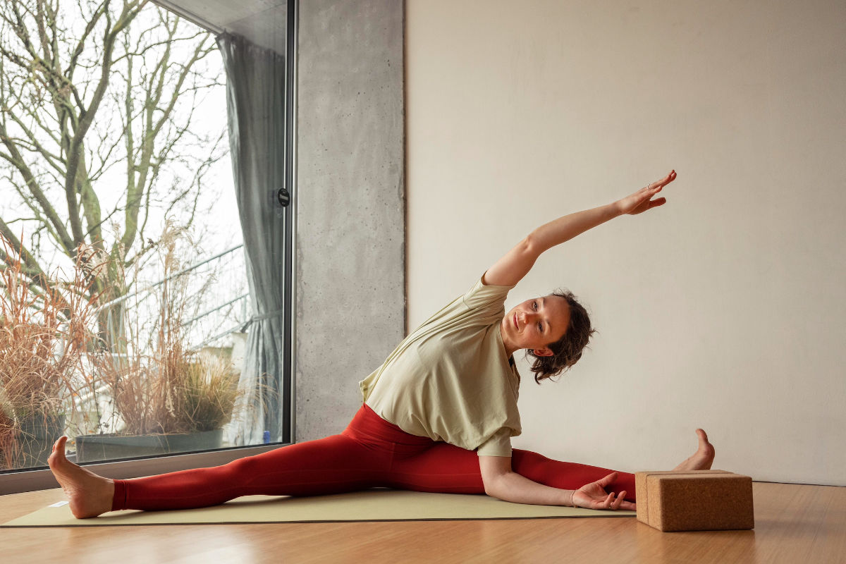 Eine Yogalehrerin in ihrem Yogastudio in einer Pose auf der Matte vor einem Fenster.
