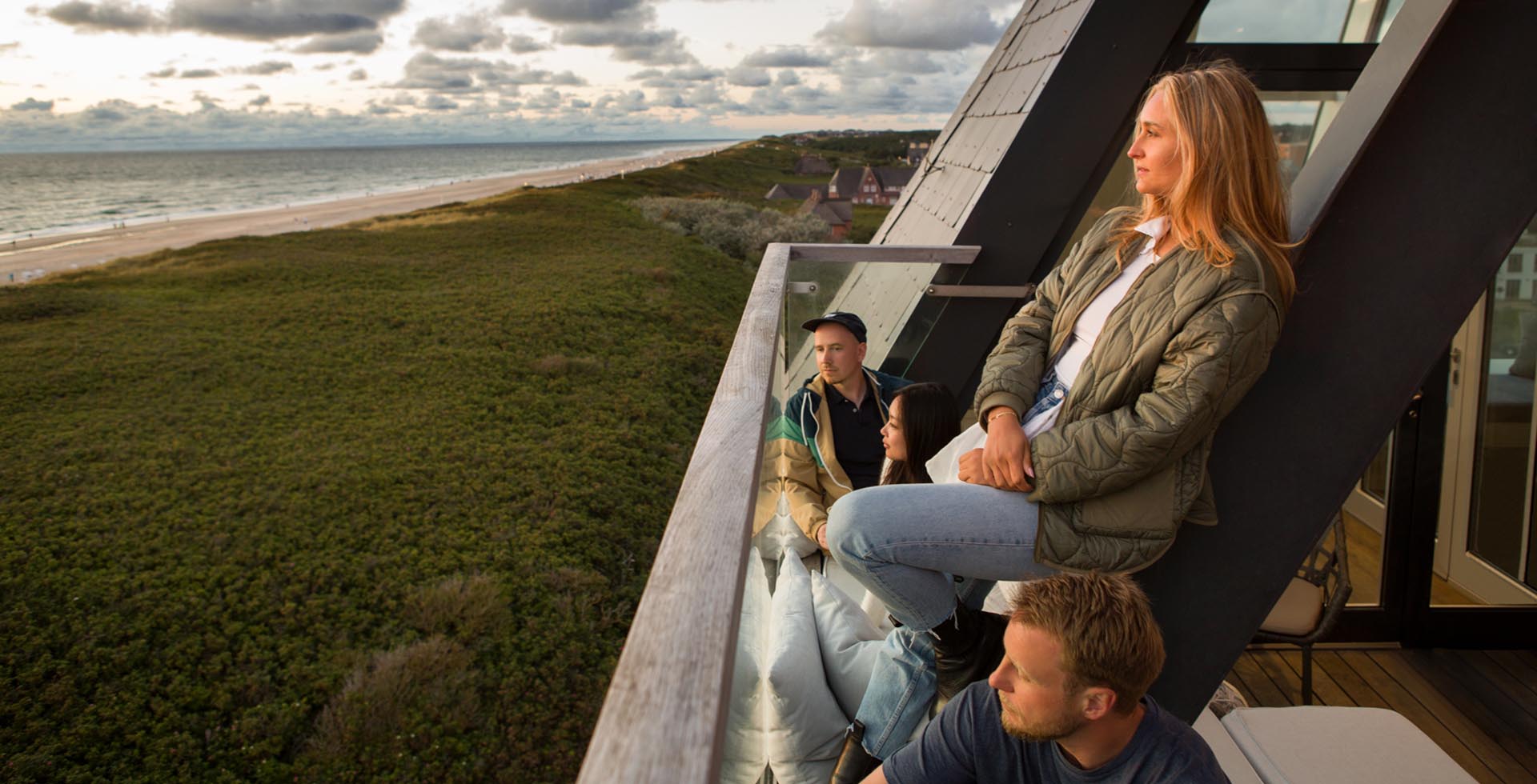Gäste genießen die Weite der Nordsee und den einzigartigen Dünenblick vom Balkon des Wyn. Strandhotels auf Sylt.