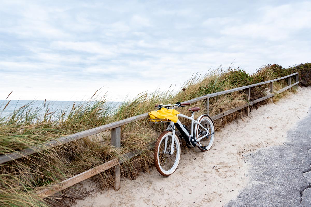 Fahrrad angelehnt an eine Holzplanke mit Blick auf Dünen und die Nordsee in der Nähe des Wyn. Strandhotel auf Sylt.