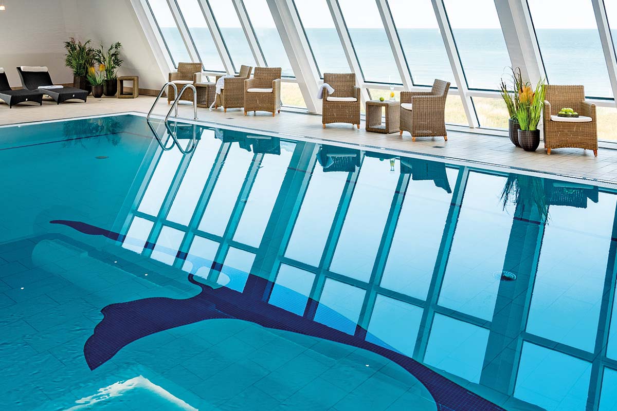 Heated pool in the day spa at the Wyn. Strandhotel Sylt with large windows and a view of the North Sea.