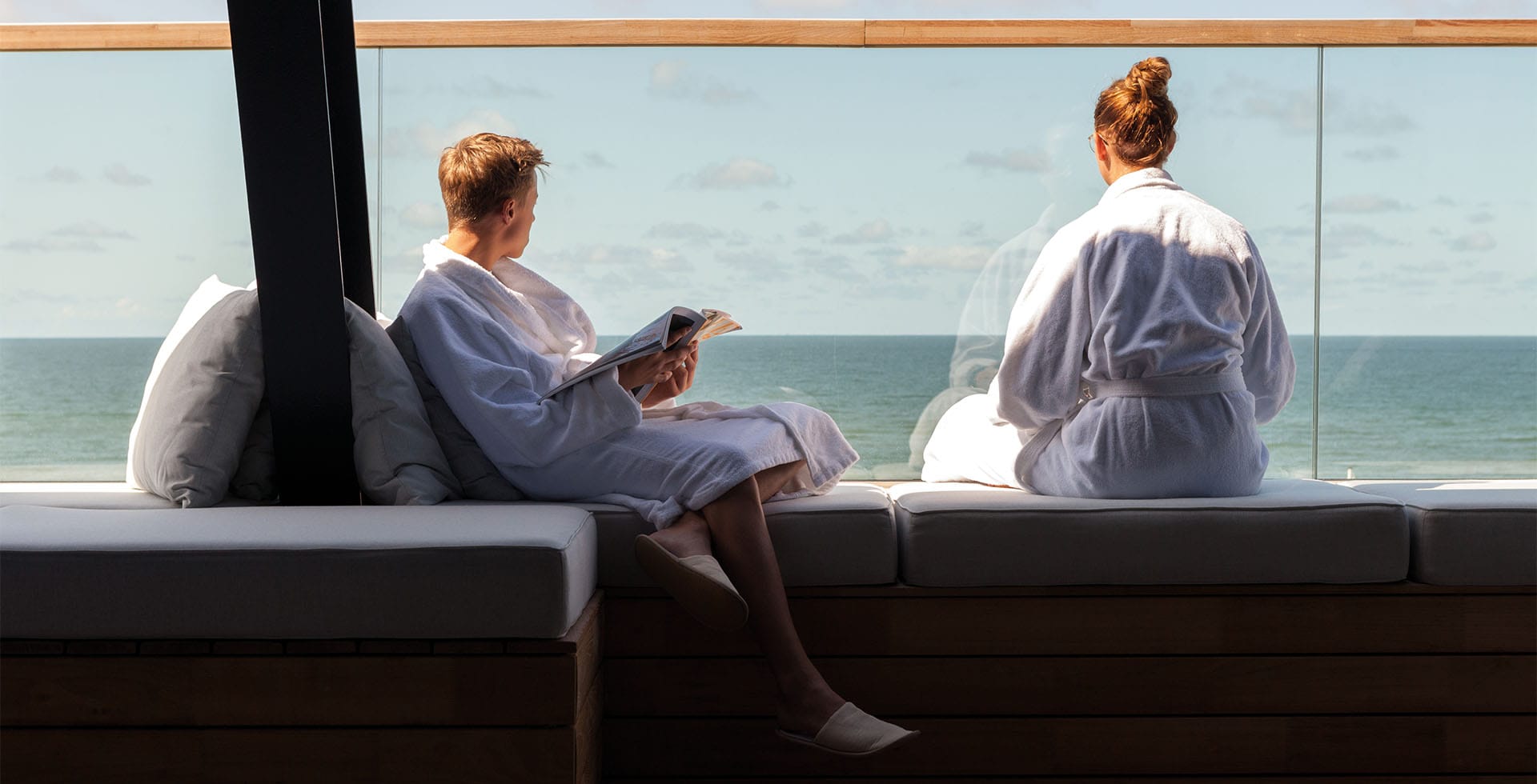 Wellness area at the Wyn. Strandhotel Sylt with guests in bathrobes and a panoramic view of the North Sea.