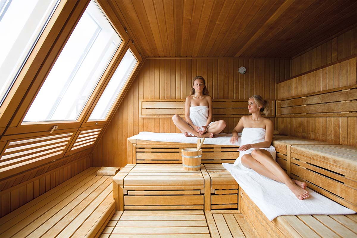 Two women relax in the sauna of the day spa at the Wyn Strandhotel on Sylt with large windows and light.