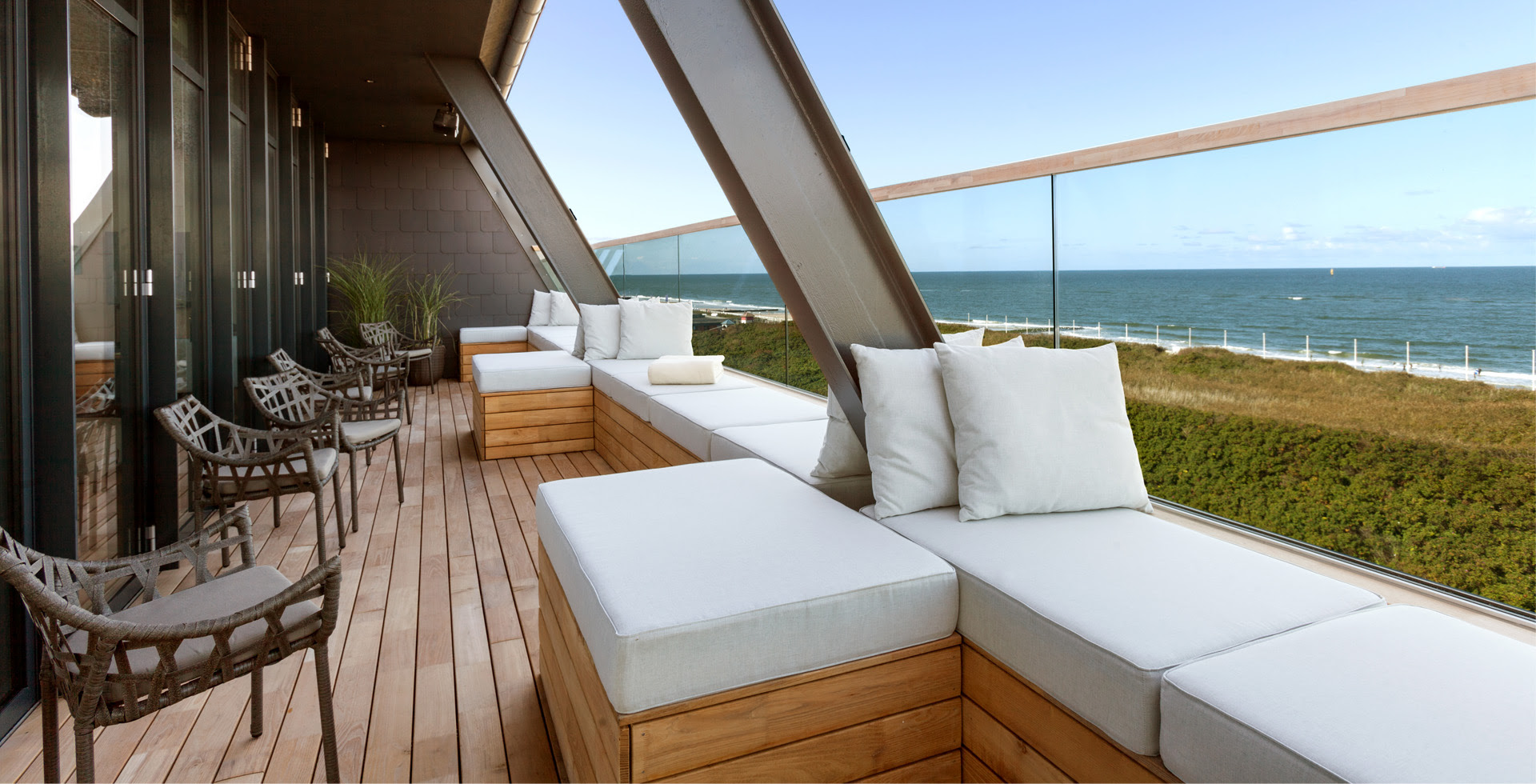 Terrasse mit gemütlichen Loungemöbeln und Glasfront im Wyn. Strandhotel auf Sylt mit Blick auf die Nordsee.