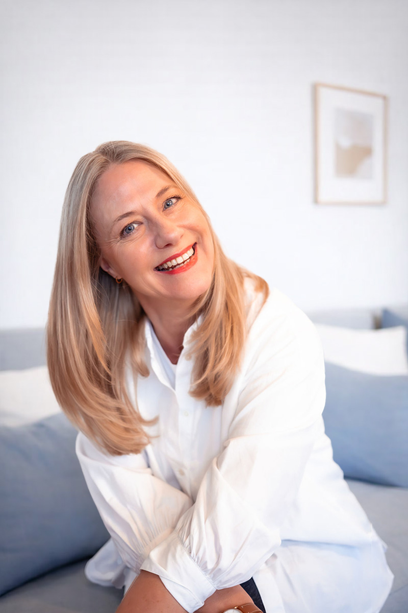 Gastgeberin des Women’s Health Day Sylt, Christiane Winter-Thumann sitzt lächelnd auf einem Sofa im Wyn. Strandhotel.